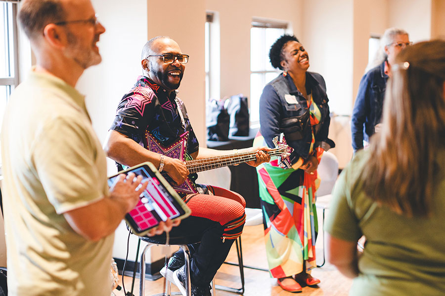 Teachers and musicians (one with a guitar) sining and laughing