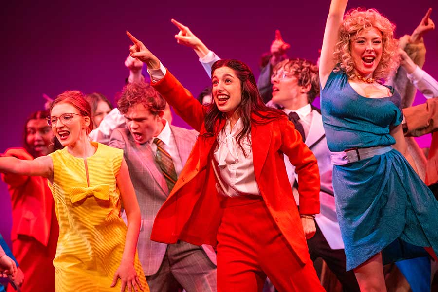 Student cast of "9 to 5" dancing in colorful costumes